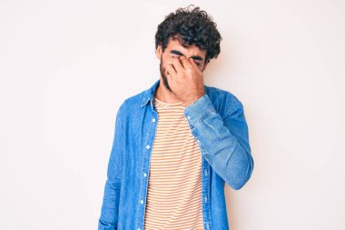 Kıvırcık saçlı, sıradan kot ceket giyen, burnu ve gözleri ovuşturmaktan yorgun, yorgun ve başı ağrıyan yakışıklı bir genç. Stres ve hüsran kavramı. 