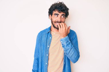 Kıvırcık saçlı, sıradan kot ceket giyen, gergin ve elleri ağız yiyen yakışıklı bir genç. anksiyete. 