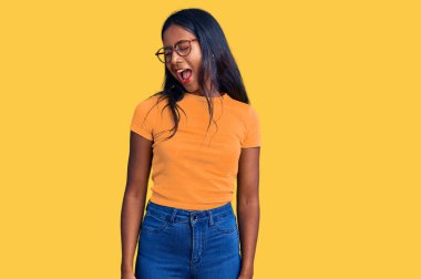 Gündelik kıyafetler ve gözlük takan genç Hintli kız kameraya seksi bir ifadeyle bakıyor, neşeli ve mutlu bir yüzle.. 