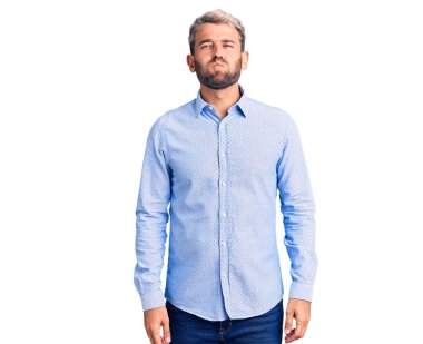 Zarif gömlek giyen yakışıklı sarışın adam komik yüzlü yanakları şişiriyor. Havayla şişmiş ağız, çılgın bir ifade.. 