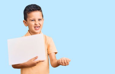 Küçük şirin çocuk elinde boş bir alanda karton pankart tutuyor gururla haykırıyor, zaferi ve başarıyı kutluyor kollarını kaldırarak heyecanlanıyor. 