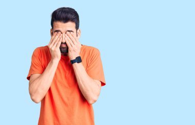 Sakallı, sıradan tişörtler giyen, yorgunluk ve baş ağrısı için gözlerini ovuşturan, uykulu ve yorgun ifadeli genç yakışıklı bir adam. görme sorunu 