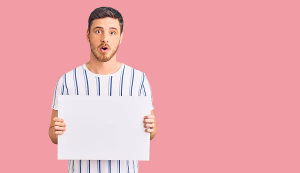 Guapo Joven Con Oso Sosteniendo Banner Vacío Blanco Asustado Sorprendido — Foto de Stock