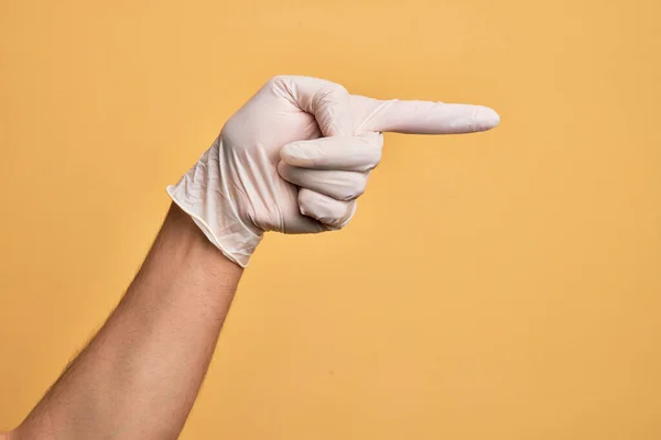 Mão Homem Jovem Caucasiano Com Luva Médica Sobre Fundo Amarelo — Fotografia de Stock