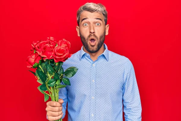 Genç Sarışın Romantik Bir Adam Kırmızı Arka Planda Güzel Güller — Stok fotoğraf