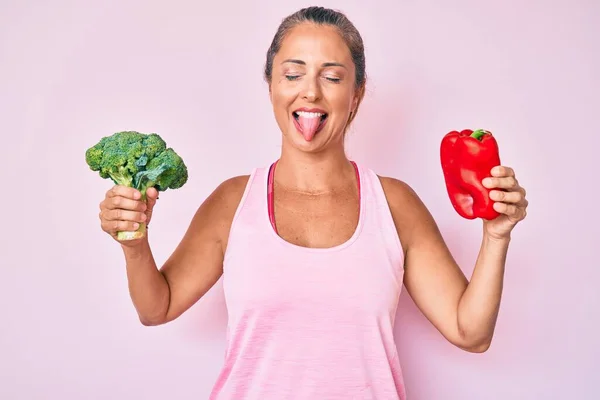 Middle Age Hispanic Woman Holding Broccoli Red Pepper Sticking Tongue — Stock Photo, Image