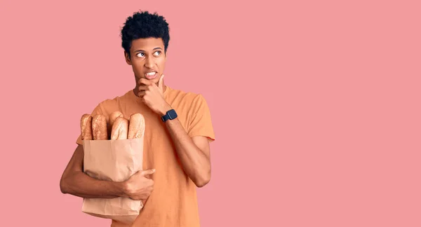 Ung Afrikansk Amerikansk Man Håller Papperspåse Med Bröd Tänkande Orolig — Stockfoto