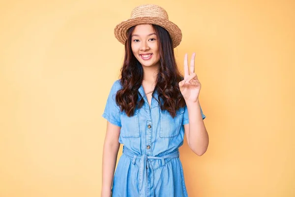 年轻美丽的中国姑娘头戴夏帽 带着自信和快乐的微笑 用手指指了指二号 — 图库照片
