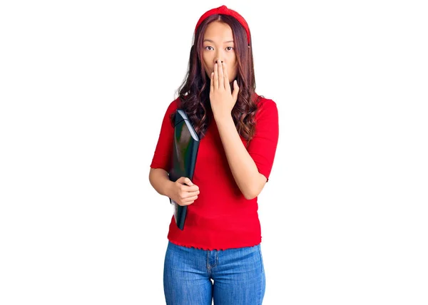 年轻美丽的中国女孩戴着学生文件夹 用手捂住嘴 感到震惊和害怕犯错 惊讶的表情 — 图库照片