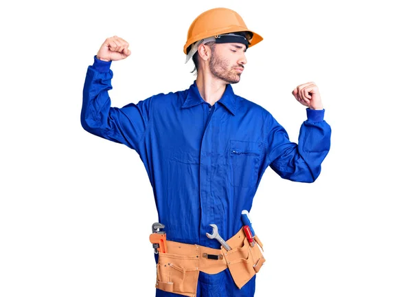 腕の筋肉を示す労働者の制服を着た若いヒスパニック系の男は誇りに思って笑う フィットネスのコンセプト — ストック写真