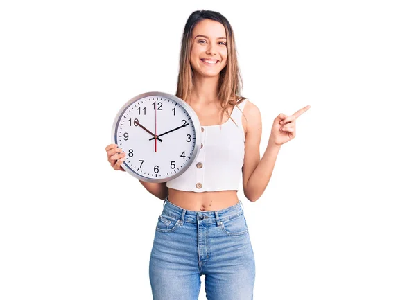 Young Beautiful Girl Holding Big Clock Smiling Happy Pointing Hand — Stock Photo, Image