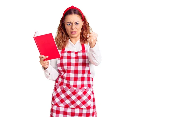 Ung Latinamerikansk Kvinna Bär Förkläde Hålla Recept Bok Irriterad Och — Stockfoto