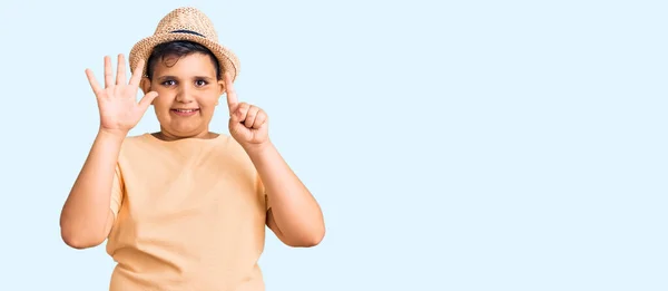 夏の帽子とハワイの水着を身に着けている小さな男の子表示し 指で指摘番号6ながら 自信と幸せ笑みを浮かべて — ストック写真