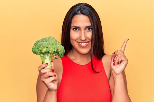 Ung Vacker Brunett Kvinna Håller Broccoli Ler Glad Pekar Med — Stockfoto