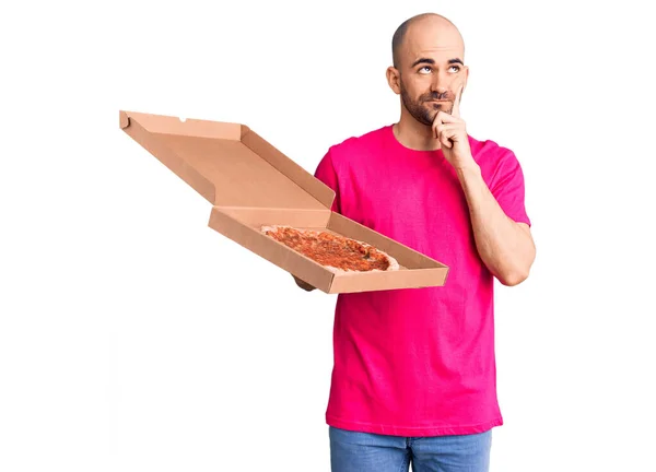 Mladý Pohledný Muž Držící Ruce Krabici Pizzy Vážný Obličej Přemýšlející — Stock fotografie