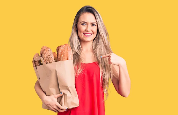 Jovem Bela Mulher Loira Segurando Saco Papel Com Pão Apontando — Fotografia de Stock