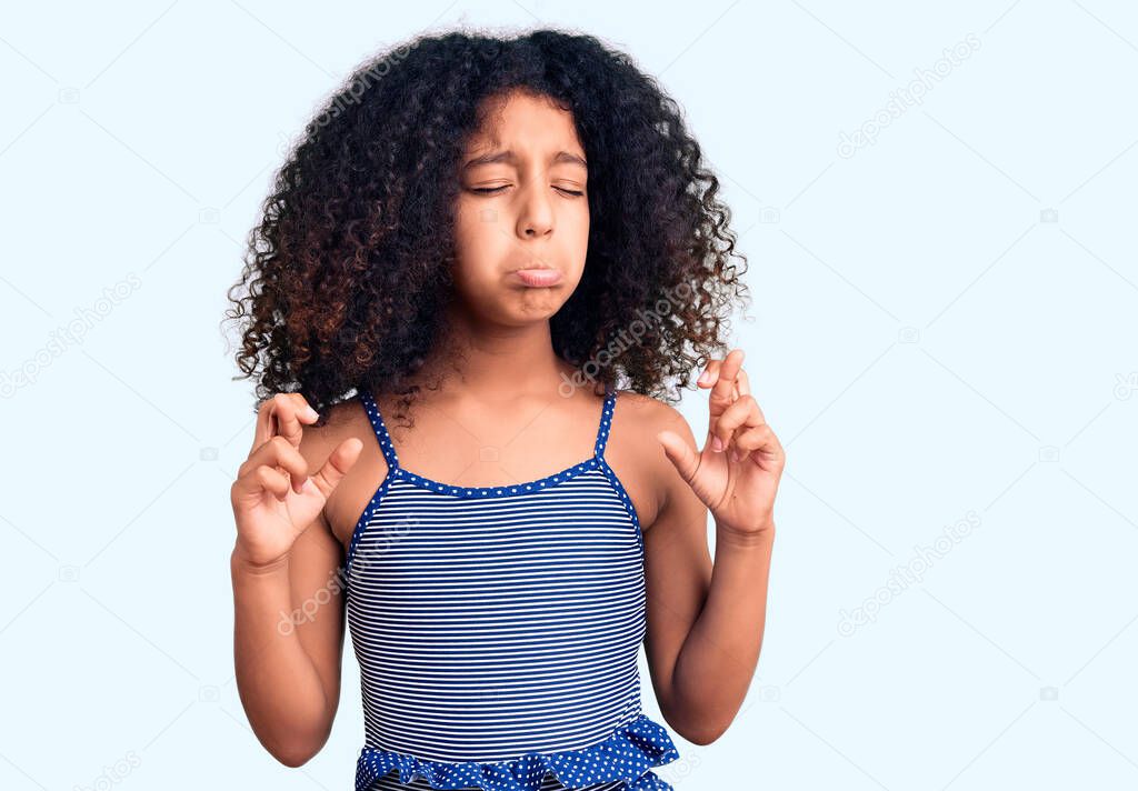 African american child with curly hair wearing swimwear gesturing finger crossed smiling with hope and eyes closed. luck and superstitious concept. 