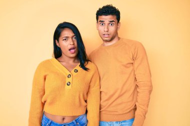 Güzel, Latin, genç bir çift. Şok yüzlü, günlük kıyafetler giyiyorlar. Şüpheci ve alaycı görünüyorlar. 