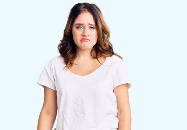 Beyaz bir tişört giyen genç, güzel, beyaz bir kadın sıkıntılı ve endişeli, sinirli ve korkmuş. hüzünlü ifade. 
