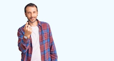 Gündelik kıyafetler giyen genç yakışıklı adam seni buraya çağırıyor. El kol hareketi yap. Mutlu bir şekilde karşıla ve gülümse. 