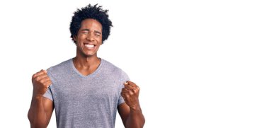 Başarı için heyecanlı, kolları havada ve gözleri kapalı, zafer kutlamaları için gülümseyen Afro saçlı yakışıklı Amerikalı adam. Kazanan konsept. 
