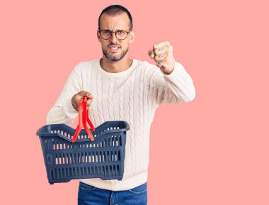 Elinde alışveriş sepeti tutan genç yakışıklı adam öfkeyle bağırıyor, öfkeyle bağırıyor ve el kaldırıyor. 