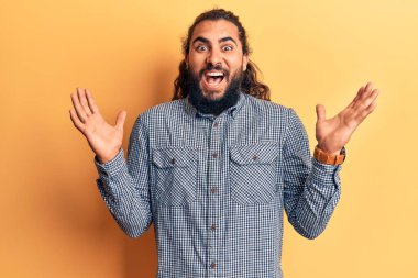 Gündelik kıyafetler giyen genç Arap adam zaferi mutlu bir gülümsemeyle kutluyor ve kazanan ifade ellerini kaldırarak ifade ediyor. 