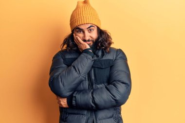 Genç Arap adam kışlık giysiler giyip kollarını kavuşturarak depresyondan sıkılmış ve yorgun görünüyor.. 