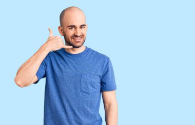 Gündelik tişört giyen, gülümseyen, el ve parmaklarıyla telefonla konuşan genç, yakışıklı bir adam. iletişim kavramları. 