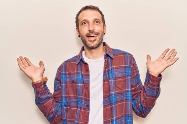 Gündelik kıyafetler giyen genç yakışıklı adam zaferi mutlu bir gülümsemeyle ve kazanan yüz ifadesiyle kutluyor. 