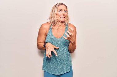 Orta yaşlı, beyaz, sarışın, spor kıyafeti giyen, tiksindirici, tiksindirici, tiksindirici bir yüz ifadesi takınan bir kadın.. 