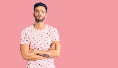 Gündelik kıyafetler giyen, kuşkucu ve gergin genç ve yakışıklı bir adam. Yüzünde çapraz kollu tasvip etmeyen bir ifade. negatif kişi. 