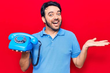 İspanyol asıllı genç adam elinde klasik bir telefonla başarıyı mutlu bir gülümsemeyle kutluyor ve kazanan el kaldırarak ifade ediyor. 