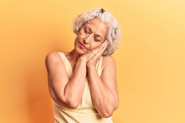 Yaşlı, gri saçlı, günlük kıyafetler giyen, uyuyan, yorgun, hayal kuran, elleriyle poz veren, kapalı gözlerle gülümseyen bir kadın.. 