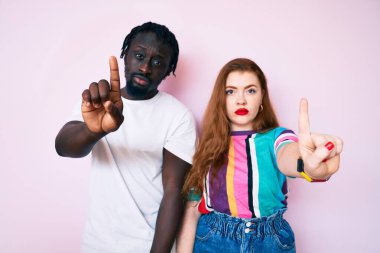 Irklar arası çiftler, gündelik giysiler giyip parmaklarını havaya kaldırıyorlar ve kızgın bir ifade takınıyorlar. 