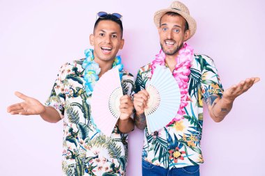 Yazlık tişört giyen iki genç eşcinsel zaferi mutlu bir gülümsemeyle ve el kaldırarak kutluyorlar. 