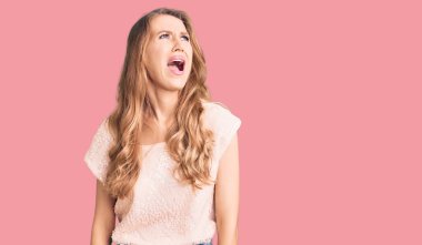 Sarışın, genç, beyaz bir kadın. Günlük kıyafetler giyiyor. Kızgın ve kızgın. Öfkeli çığlıklar atıyor. öfke ve agresif konsept. 