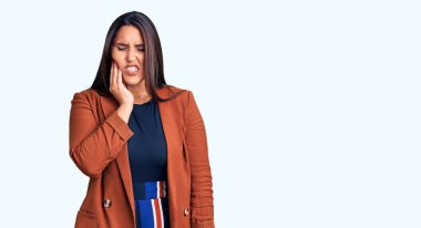 Zarif kıyafetler giyen, diş ağrısı ya da diş hastalığından dolayı acı dolu bir ifadeyle dudaklarına dokunan güzel, esmer bir kadın. dişçi 