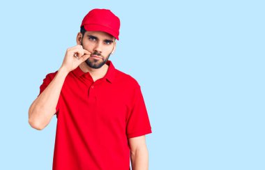 Sakallı, teslimat üniformalı, ağzı ağızlı ve dudakları parmakları fermuarlı yakışıklı bir adam. gizli ve sessiz, tabu konuşması 