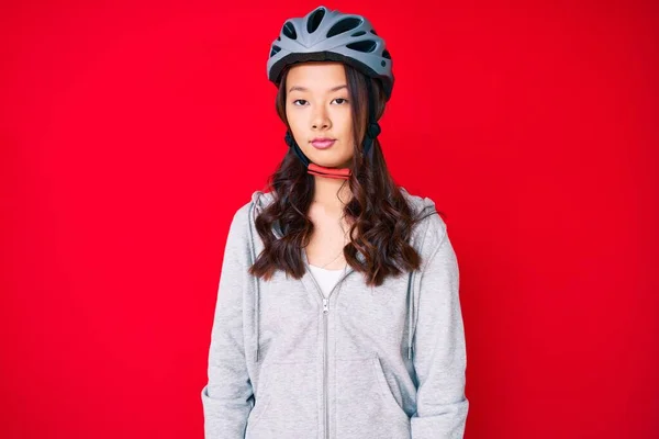 若い美しい中国の女の子が顔に深刻な表情で自転車のヘルメットを着用 カメラを見ているだけで — ストック写真