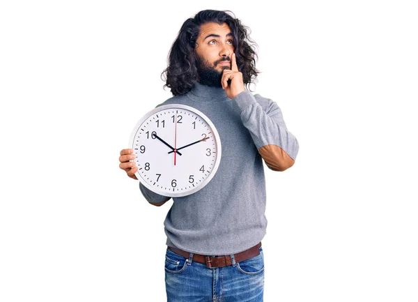 Hombre Árabe Joven Sosteniendo Cara Seria Reloj Grande Pensando Pregunta —  Fotos de Stock