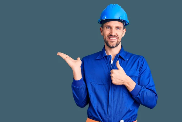 Jovem Bonito Homem Vestindo Trabalhador Uniforme Hardhat Mostrando Palma Mão — Fotografia de Stock