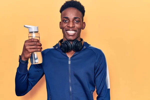Młody Afroamerykanin Odzieży Sportowej Trzymający Butelkę Wody Wyglądający Pozytywnie Szczęśliwie — Zdjęcie stockowe