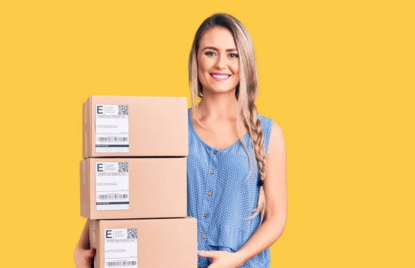 Young Beautiful Blonde Woman Holding Delivery Boxes Looking Positive Happy — Stock Photo, Image