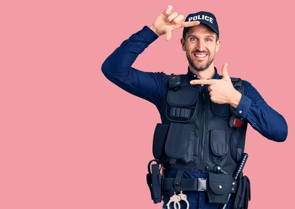 Young handsome man wearing police uniform smiling making frame with hands and fingers with happy face. creativity and photography concept.