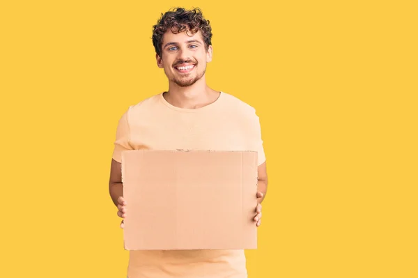 Jovem Homem Bonito Com Cabelo Encaracolado Segurando Banner Vazio Papelão — Fotografia de Stock