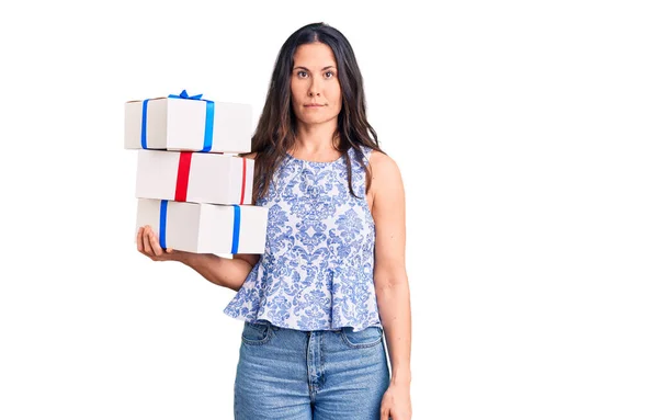 Young Beautiful Brunette Woman Holding Birthday Gift Thinking Attitude Sober — Stock Photo, Image