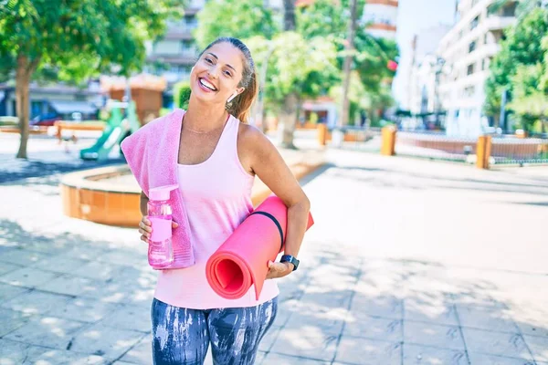 中年妇女带着瑜伽垫和一瓶水在公园里开心地笑着 — 图库照片