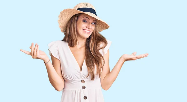 若い美しいブロンドの女性は夏のドレスを着て 腕や手で上げられ 無慈悲で混乱した表情を帽子 疑わしい概念 — ストック写真