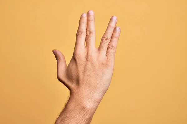 孤立した黄色の背景挨拶の上に指を示す白人の若い男の手バルカン敬礼を行う 手と指の後ろを示す フリーク文化 — ストック写真